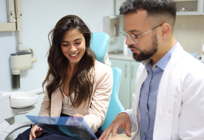 A dentist and a patient talking through treatment options in a consultation room