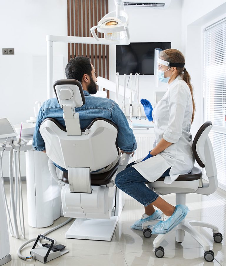 A dental treatment room with the chair, overhead light and instrument tray ready for a patient