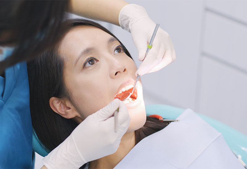 A clinician cleaning a patient's teeth during a routine dental appointment